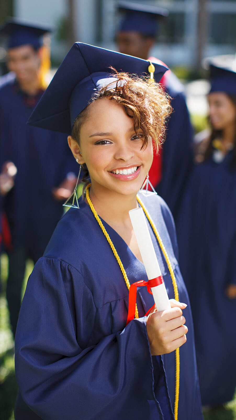 Young female student wearing a graduation cap and gown, and a dimploma in her hand.